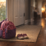Child’s backpack and shoes by a front door after daycare in the evening